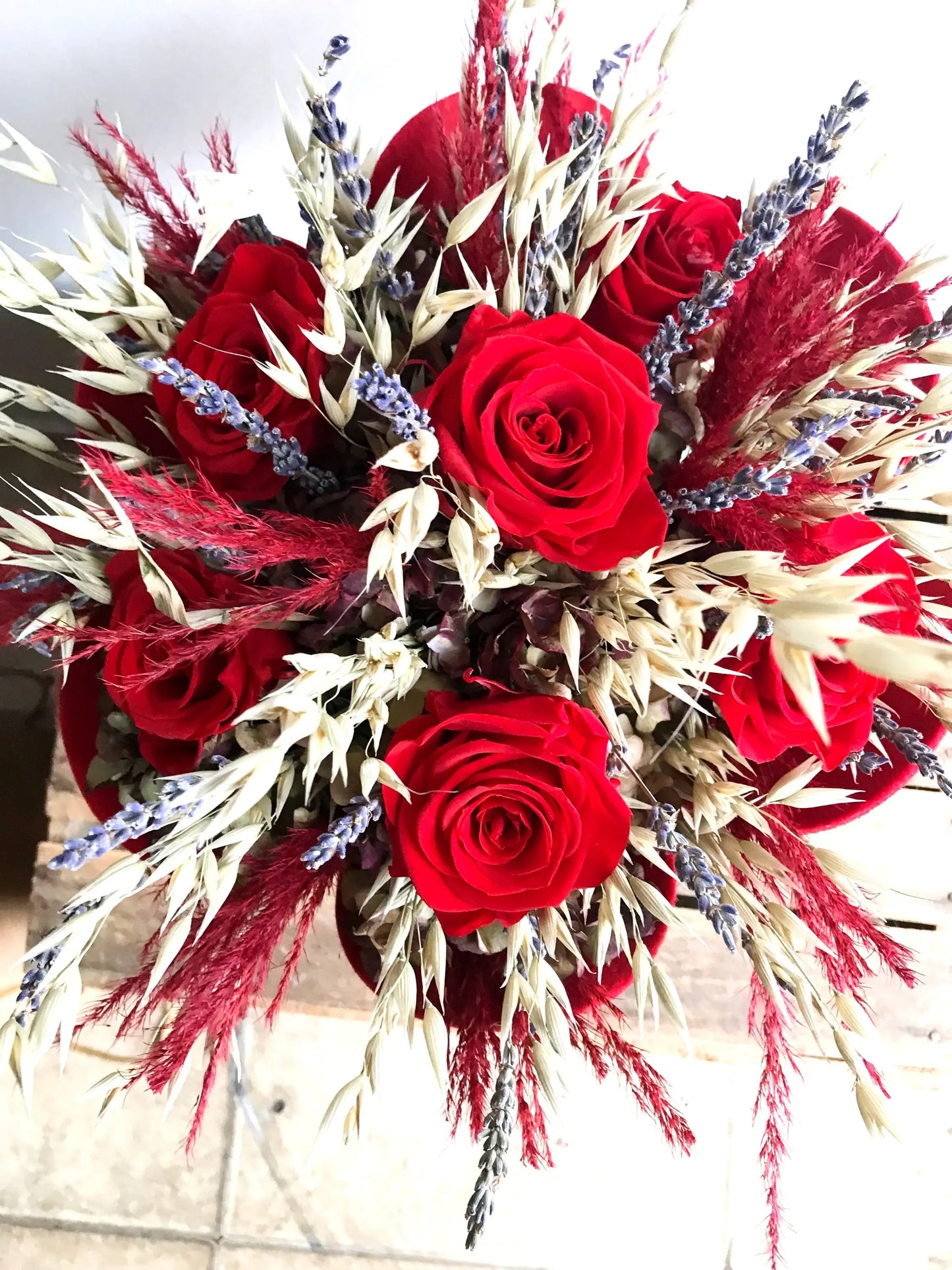 A close up image of a valentines bouquet of 6 preserved red roses and dried flowers