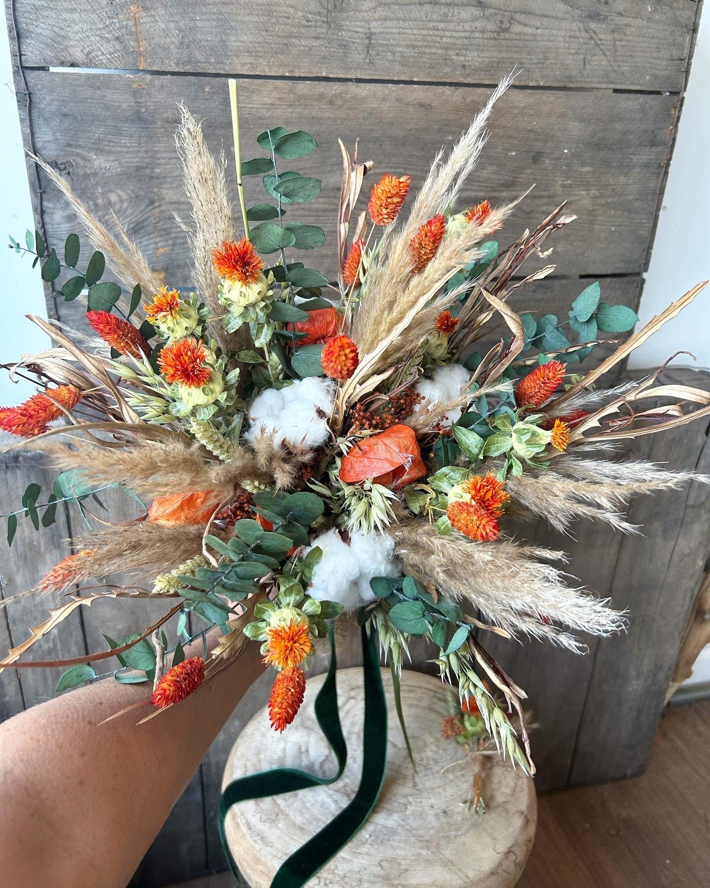 Dried flower bridal bouquet using autumn colours with orange grasses and preserved forest green eucalyptus