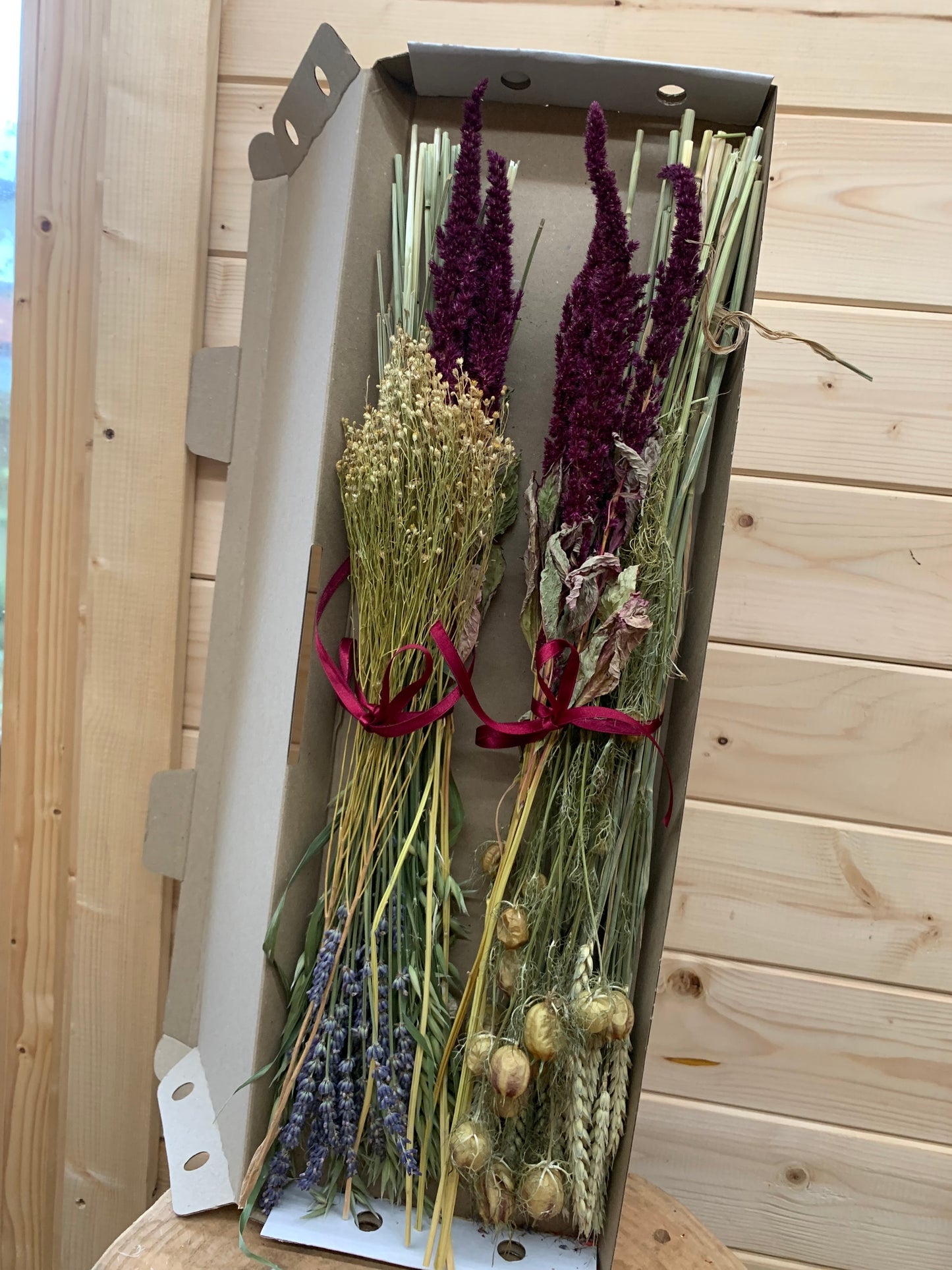 A selection of dried flowers, the contents of letterbox gift, in a cardboard box on a wooden surface