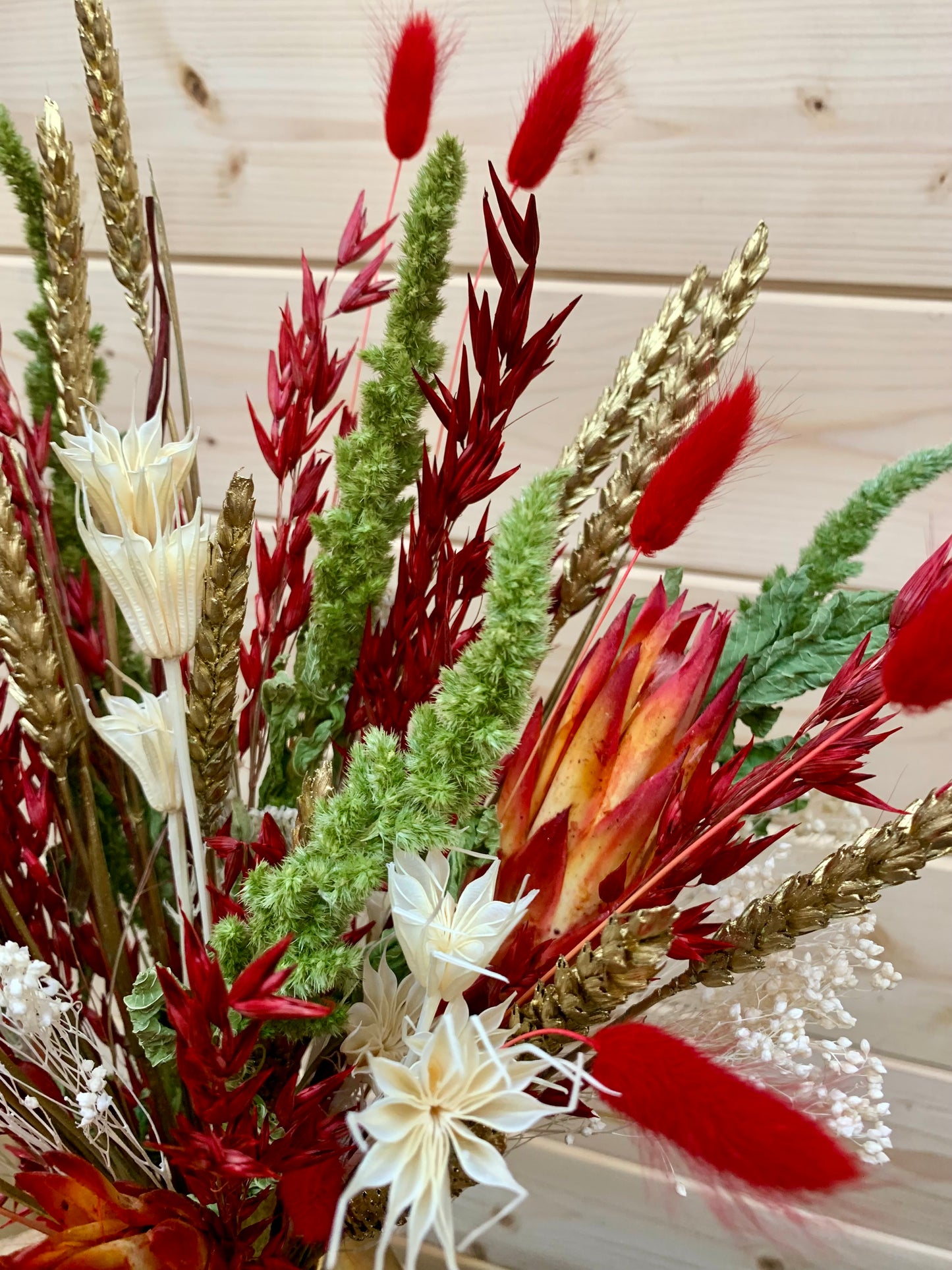 Bouquet of red, white, and green flowers with a wooden background