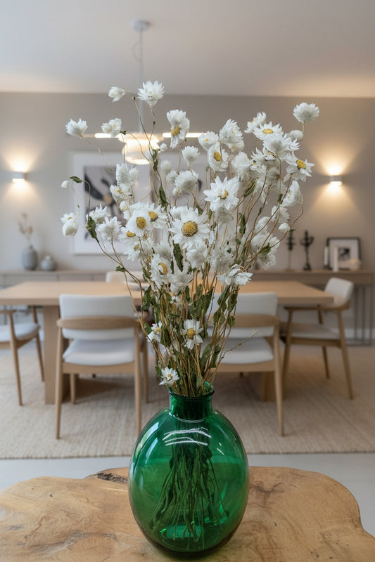 White daisies in a green vase in a neutral dining room