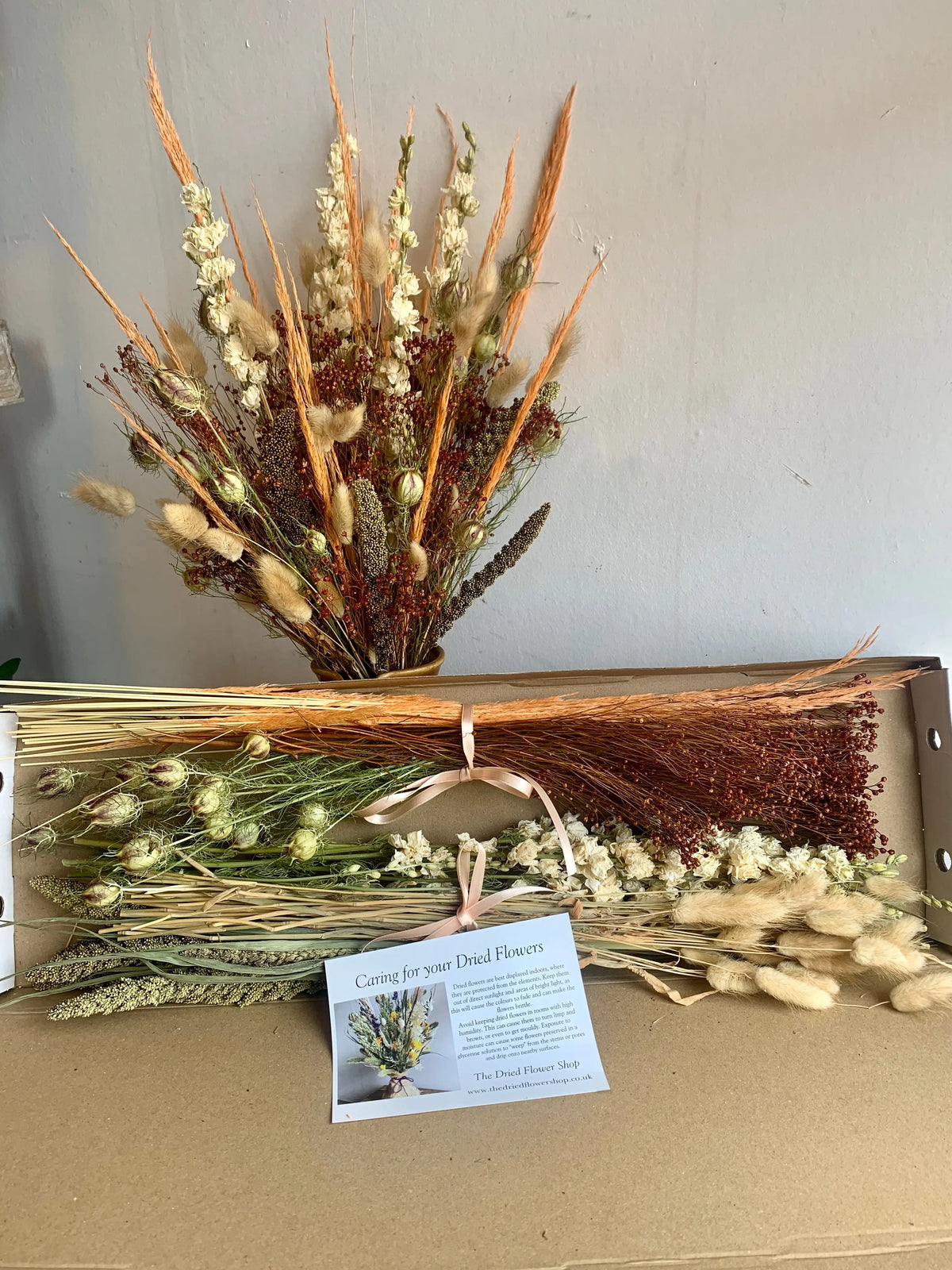 Bouquet of dried flowers with a care card label on a cardboard surface