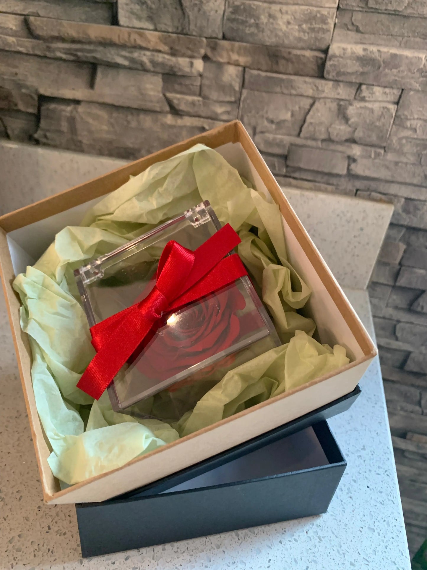 Forever red rose displayed in a perspex box in a shipping box stuffed with green tissue.