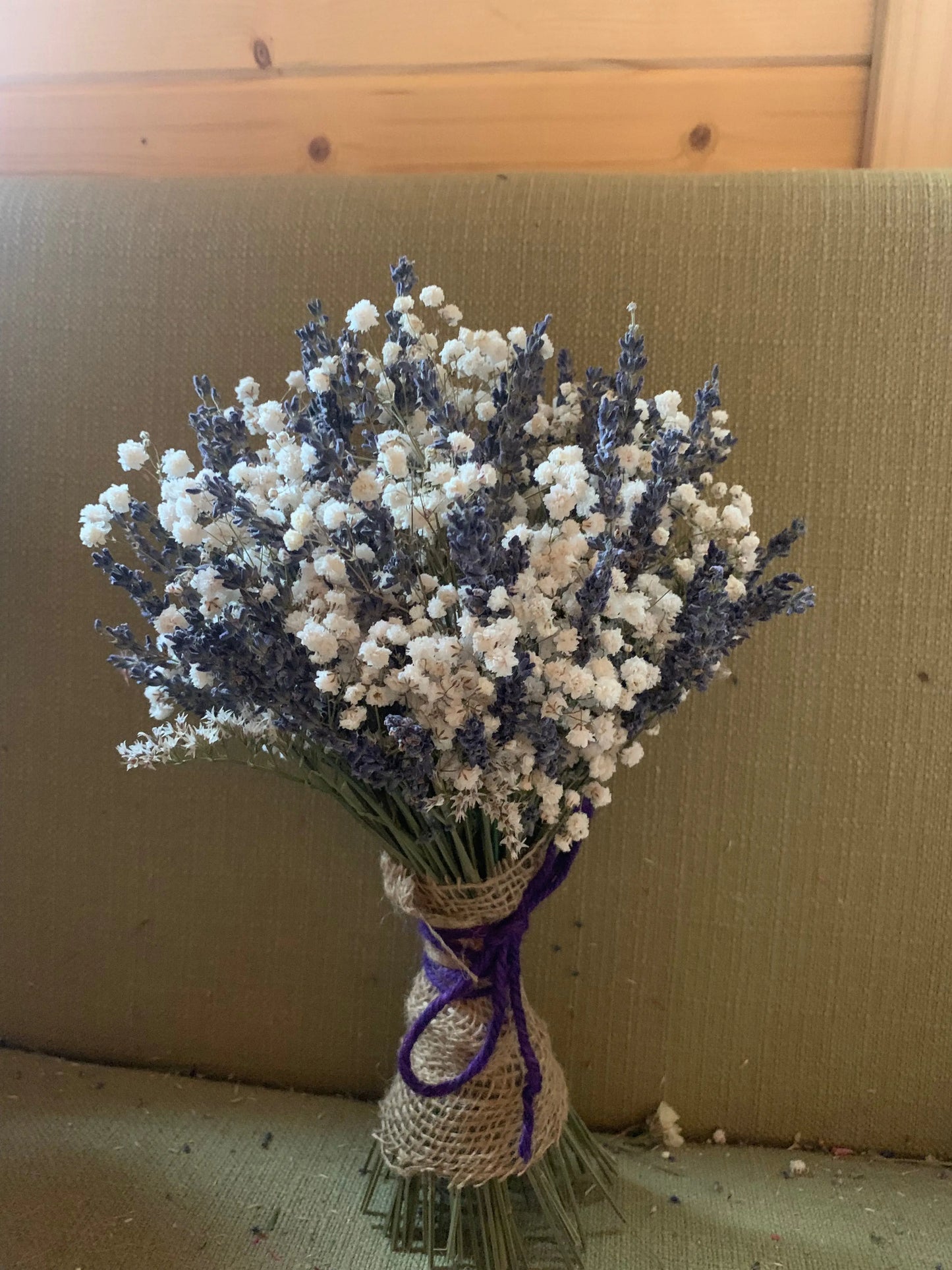 Bouquet of lavender and baby's breath with a purple twine on a textured surface.
