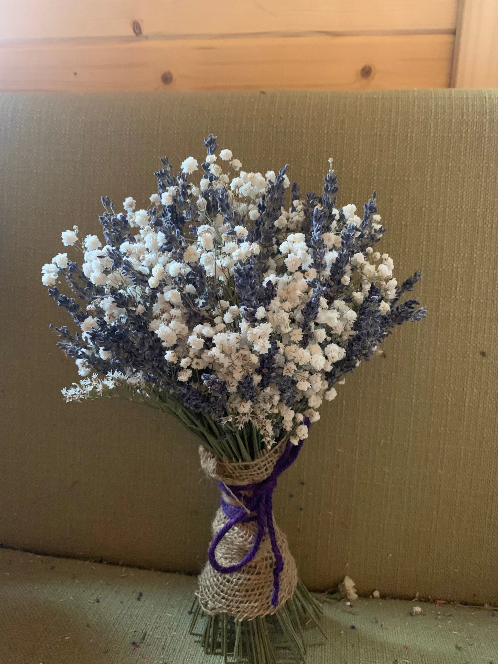 Bouquet of lavender and baby's breath with a purple twine on a textured surface.