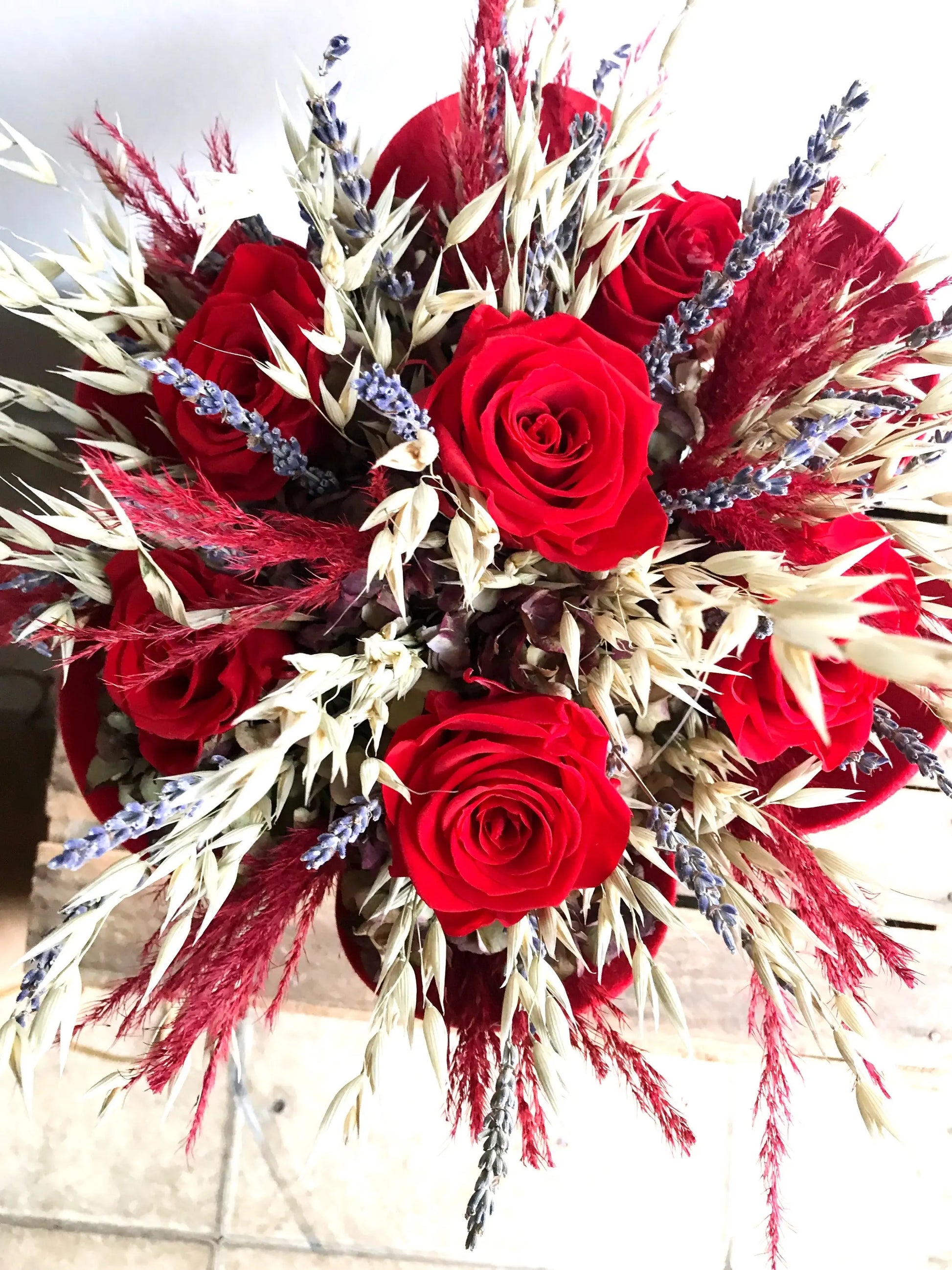 A close up image of a valentines bouquet of 6 preserved red roses and dried flowers