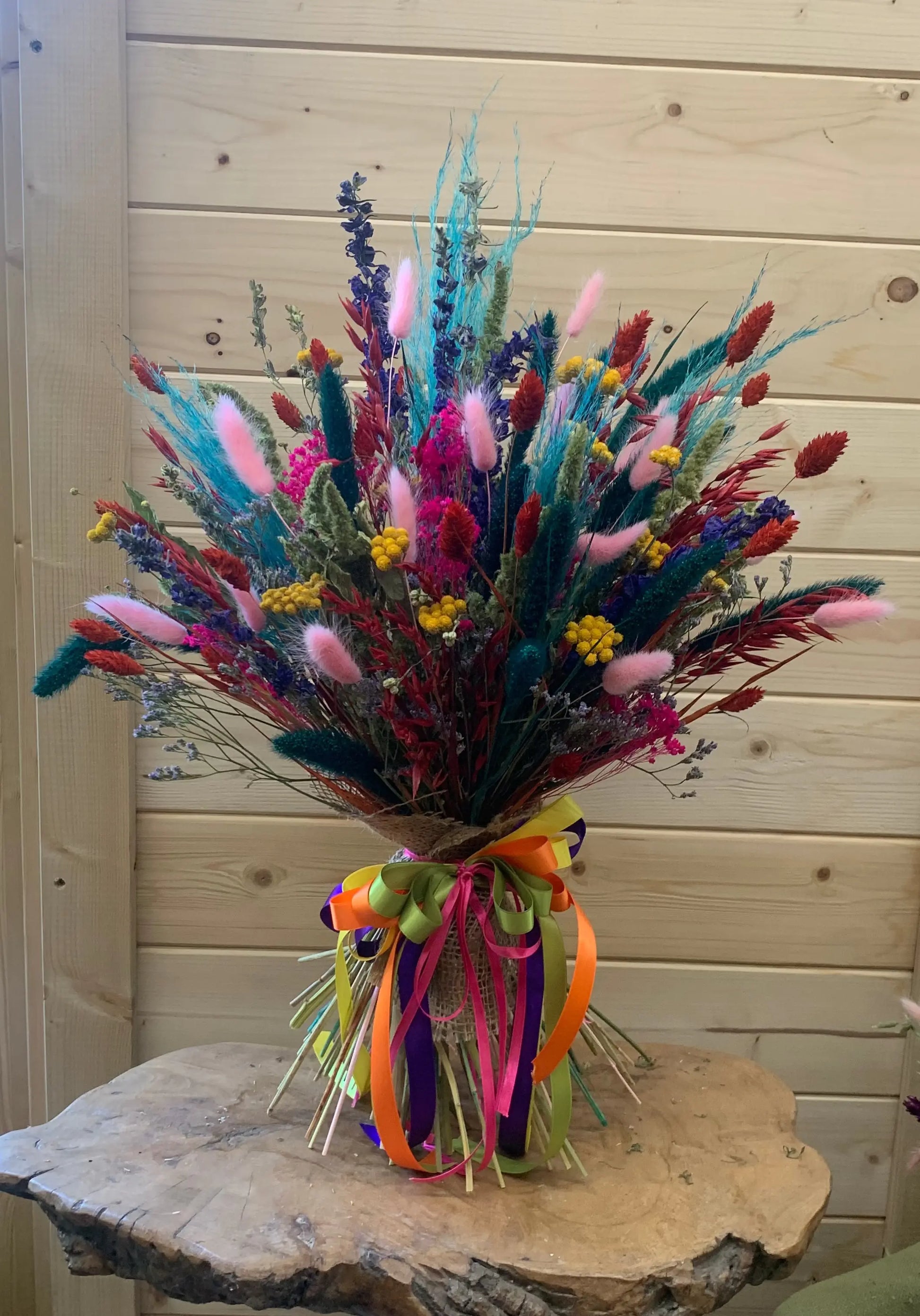 Colourful bouquet of flowers on a wooden pedestal against a wooden wall.